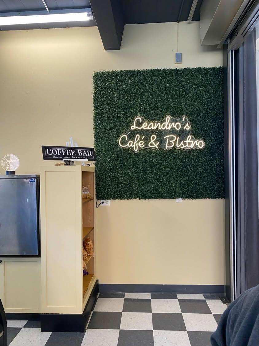 The Leandro's Cafe and Bistro neon sign on a green hedge wall